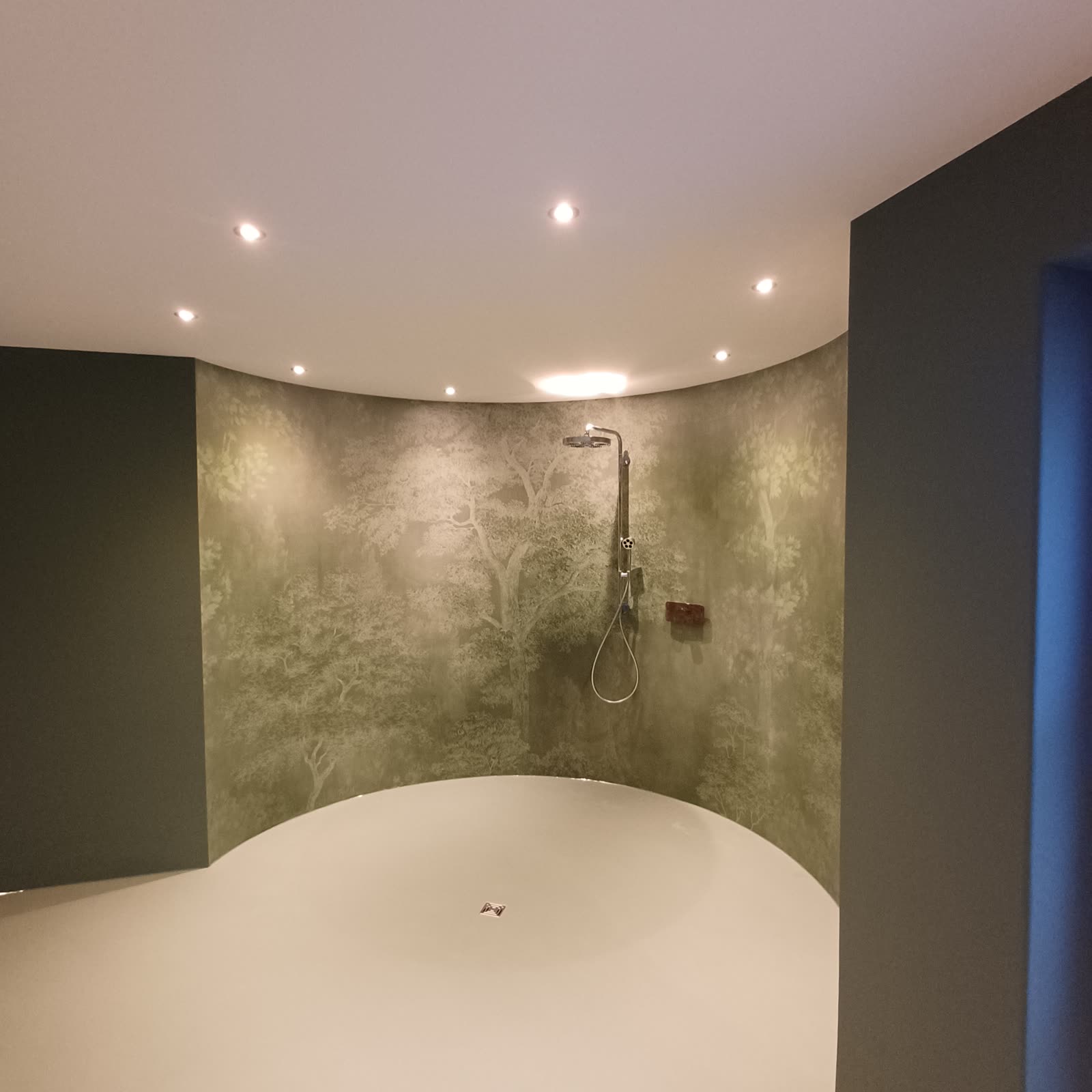 Runde Dusche mit fugenlosem Boden und tapezierter Wand mit Waldmotiv