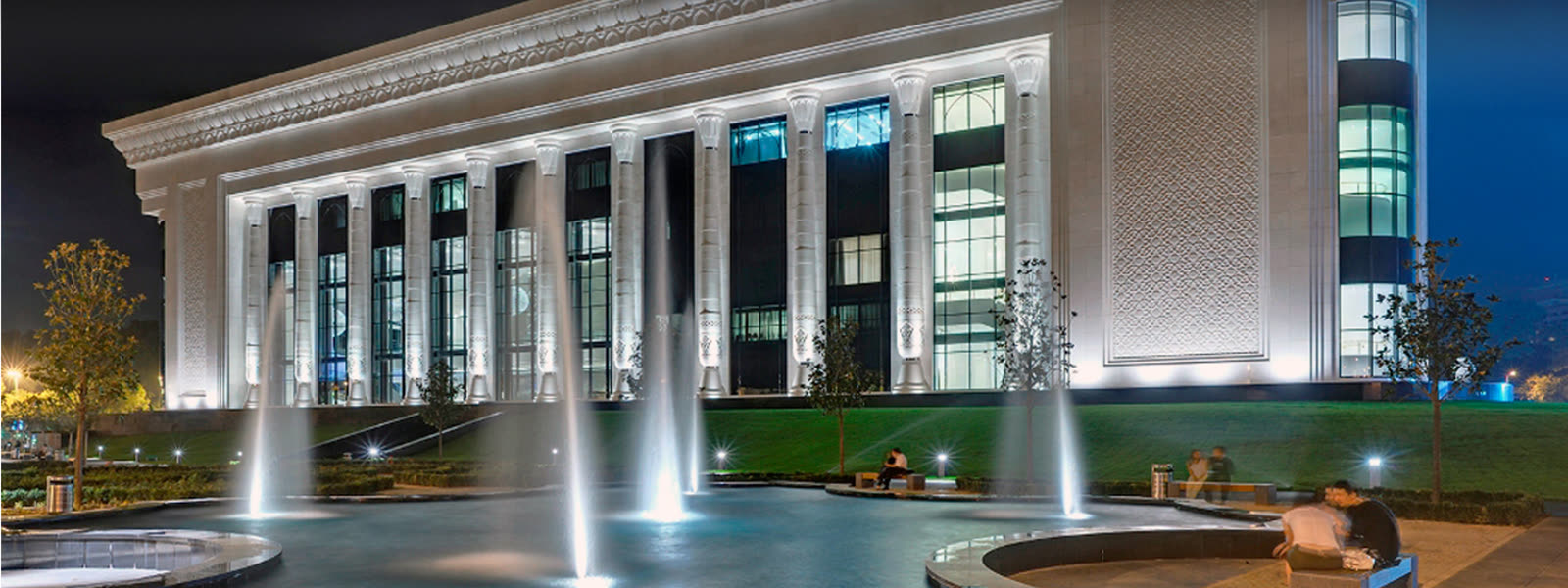 Beleuchtete Fassade eines Repräsentationsgebäudes bei Nacht mit Springbrunnen