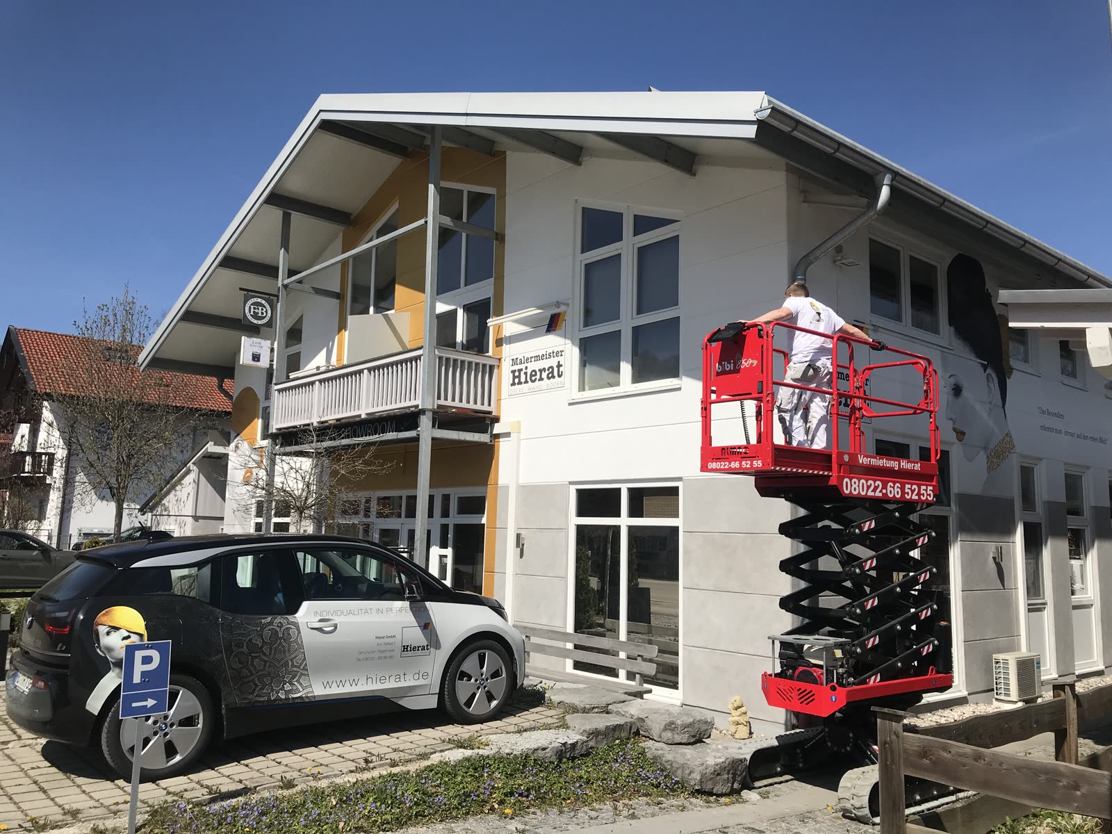 Betriebsgebäude von Malermeister Hierat mit Firmenwagen und Hebebühne